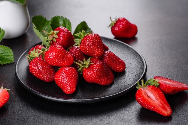 Belle fragole fresche succose sulla superficie di cemento del tavolo