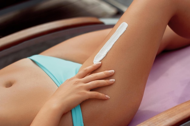 Belle gambe con crema solare per la cura della pelle Donna che applica crema solare sulla pelle delle gambe Crema solare sui piedi