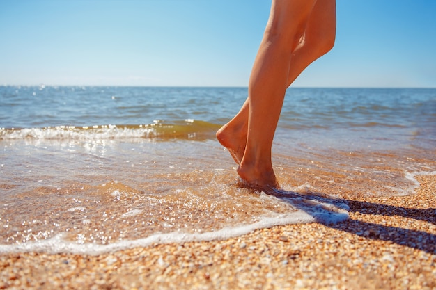 Belle gambe di una bella ragazza che cammina in acqua