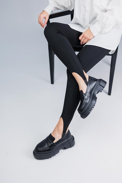 Belle gambe femminili in mocassini in pelle nera e leggings neri Scarpe da donna estive