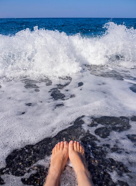 Belle gambe femminili nella schiuma dell'acqua di mare nel Mar Egeo in una giornata di sole in Grecia