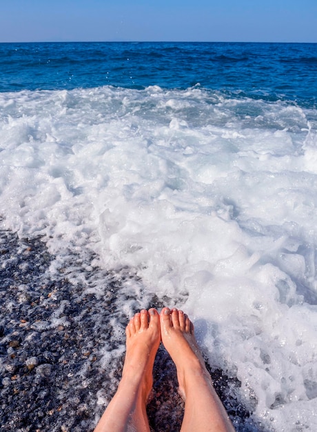 Belle gambe femminili nella schiuma dell'acqua di mare nel Mar Egeo in una giornata di sole in Grecia