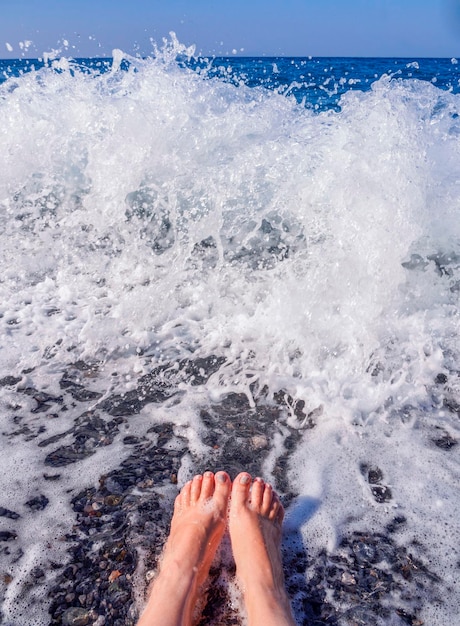 Belle gambe femminili nella schiuma dell'acqua di mare nel Mar Egeo in una giornata di sole in Grecia