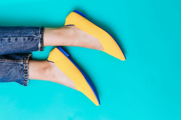 Belle gambe femminili sono vestite con eleganti scarpe gialle senza tacco Sandali estivi giallo chiaro su sfondo blu