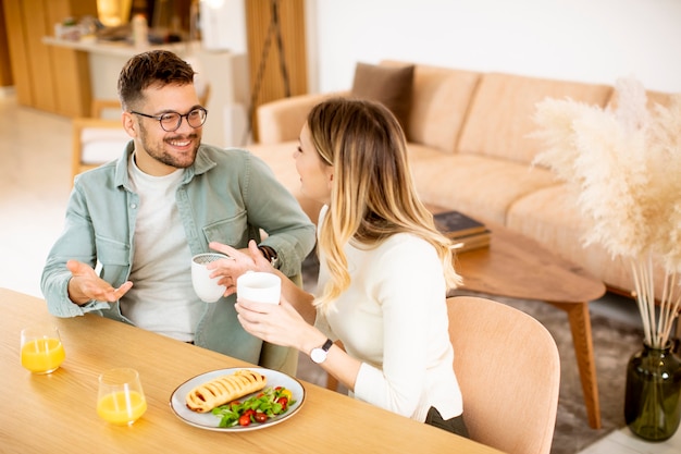 Belle giovani coppie che parlano e sorridono mentre mangiano sano a casa.