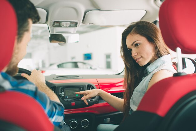 Belle giovani coppie che stanno alla concessionaria che sceglie l'auto per comprare