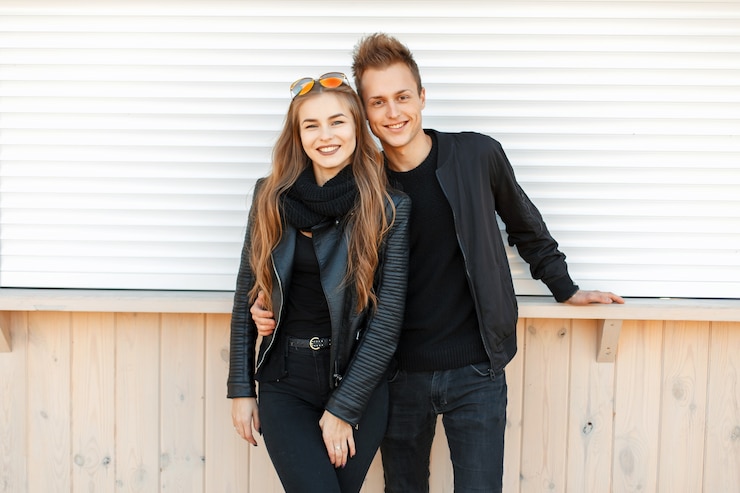 Foto belle giovani coppie felici che sorridono in vestiti alla moda alla moda vicino al muro bianco
