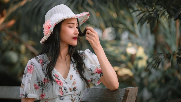 Belle giovani donne asiatiche in abiti rosa fiori retrò stili e cappello vintage seduto su legno