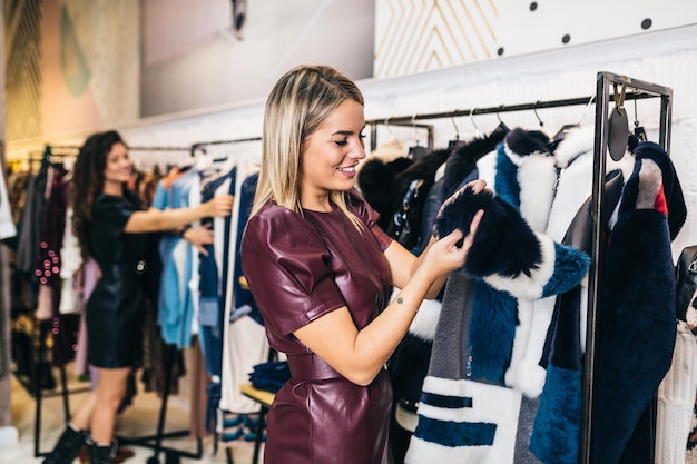 Belle giovani donne che provano vestiti eleganti in boutique costose o in un negozio.