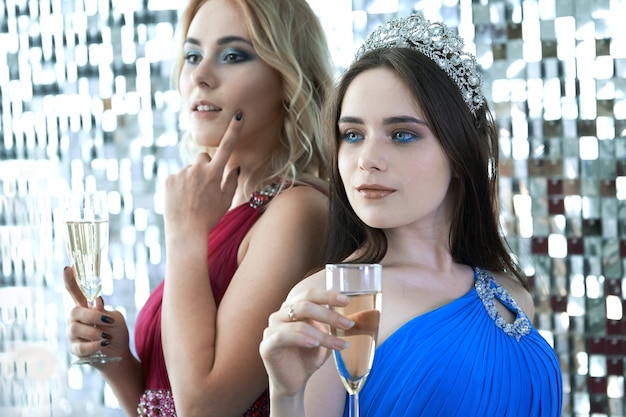 Belle giovani donne in posa con bicchieri di vino alla festa dedicata alla celebrazione di Natale o Capodanno