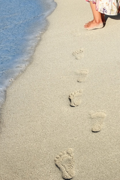 Belle impronte con i piedi sullo sfondo di sabbia