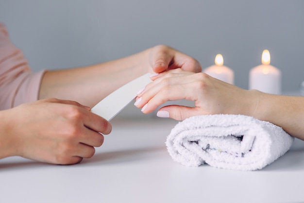 belle mani femminili che hanno manicure spa presso il salone di bellezza. Lucida le unghie usando le lime per unghie.