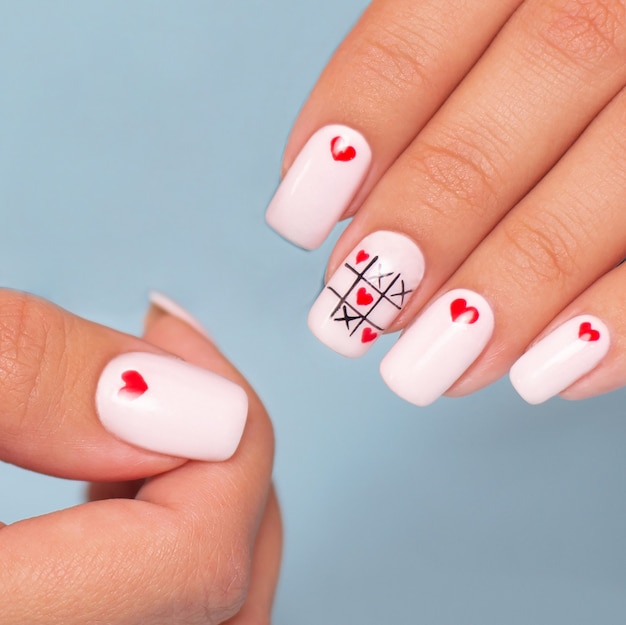 Belle mani femminili con manicure creativa, disegno dei cuori