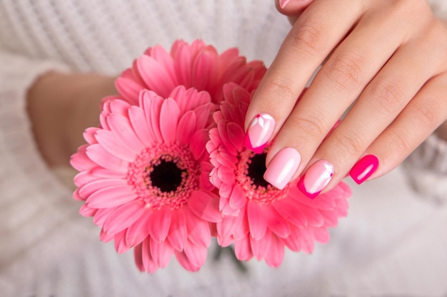 Belle mani femminili con manicure romantica unghie rosa gel polacco fiori di gerbera design