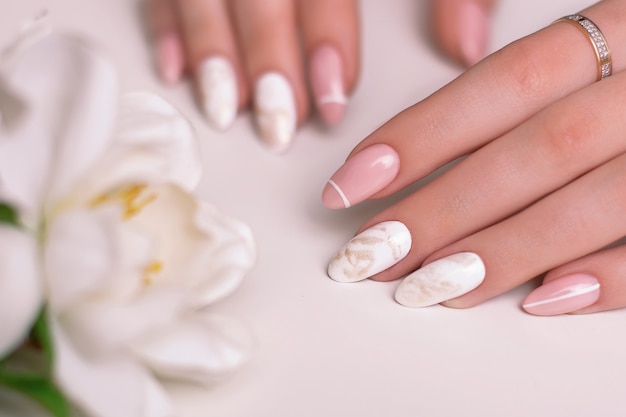 Belle mani femminili con unghie di lusso per manicure smalto gel rosa e bianco