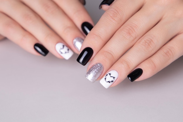 Belle mani femminili con unghie manicure nere cuore disegno su sfondo bianco