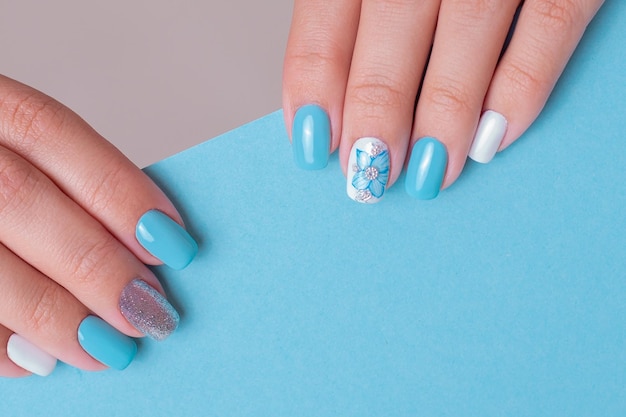 Belle mani femminili con unghie manicure romantiche, smalto gel blu e bianco
