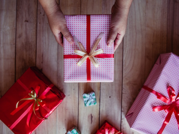 Belle mani femminili in possesso di un regalo di Natale in scatola con fiocco rosso.