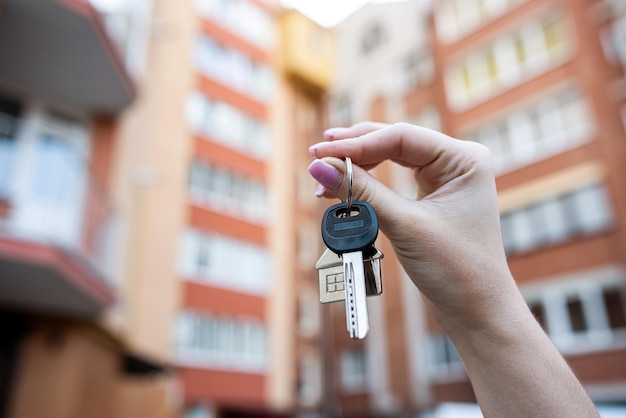 Belle mani femminili tengono le chiavi del nuovo appartamento sullo sfondo dell'edificio