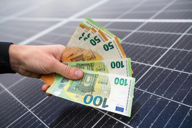 Belle mani giovani in nero tengono una grossa somma di euro pagata per i pannelli solari Concetto di elettricità verde