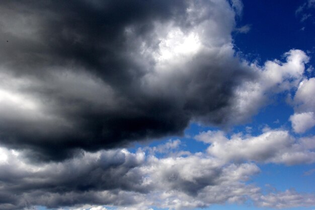 Belle nuvole bianche e scure su un cielo blu con il sole dietro le nuvole.