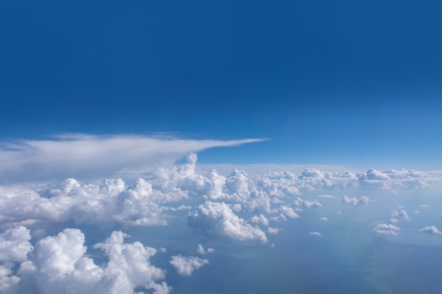 Belle nuvole bianche lanuginose cumuliformi su un cielo azzurro con sole splendente. Perfetto sfondo astratto cielo, carta da parati, layout. Alba sopra le nuvole dal finestrino dell'aereo