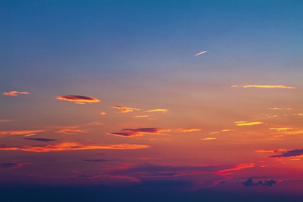 Belle nuvole rosse di tramonto luminoso nei precedenti del cielo blu