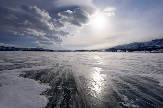 Belle nuvole sopra la superficie del ghiaccio e ventoso cumulo di neve in una giornata gelida. Lago Baikal ghiacciato.