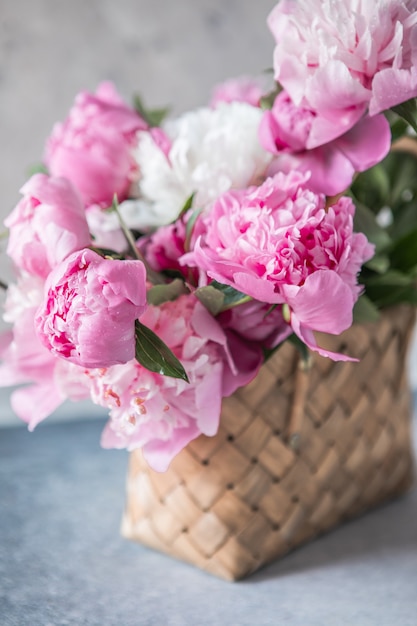 Belle peonie in cesto di vimini su tavola di legno