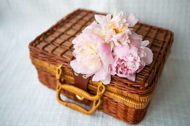 Belle peonie rosa che si trovano su una valigia di legno