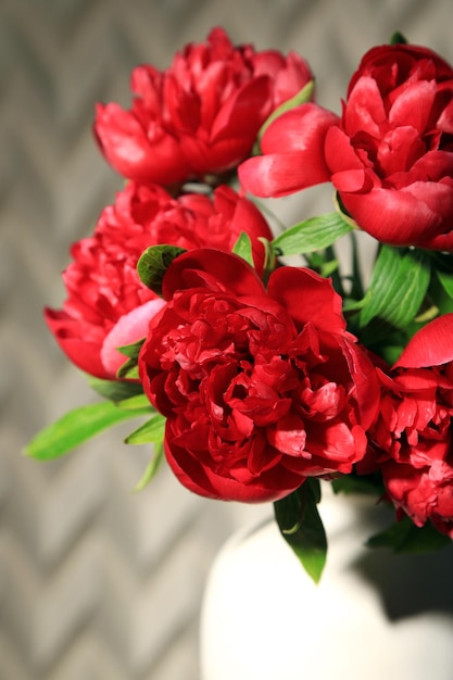 Belle peonie rosa in vaso su sfondo chiaro