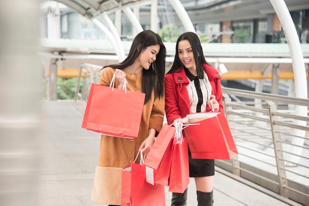 Belle ragazze che tengono i sacchetti della spesa che camminano al centro commerciale.