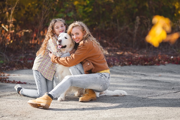 Belle ragazze con golden retriever. Due sorelle all'aperto divertendosi. Proprietari di animali domestici in autunno.