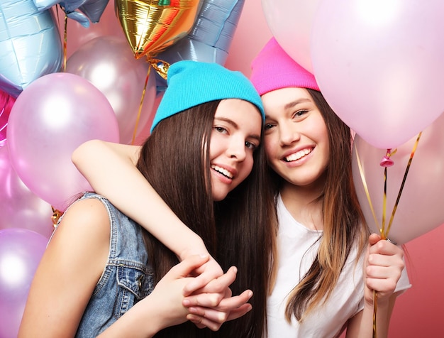 Belle ragazze con palloncini d'aria su sfondo rosa