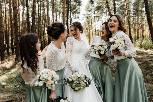 Belle ragazze ridenti in abiti da sposa tengono mazzi di fiori, damigelle, giorno del matrimonio, foto di gruppo, ragazze felici, ragazze divertenti