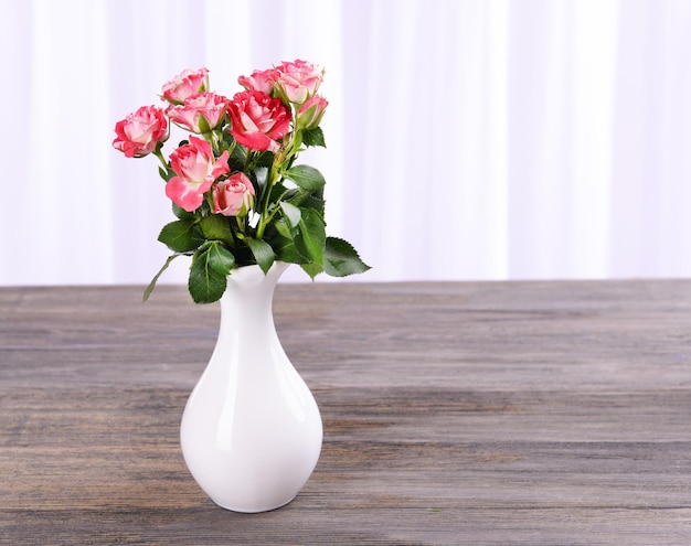 Belle rose in vaso sul tavolo su sfondo chiaro