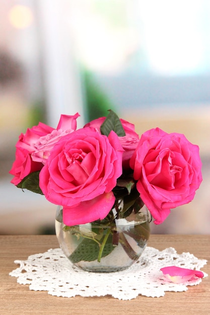 Belle rose rosa in vaso sul tavolo di legno sullo sfondo della stanza