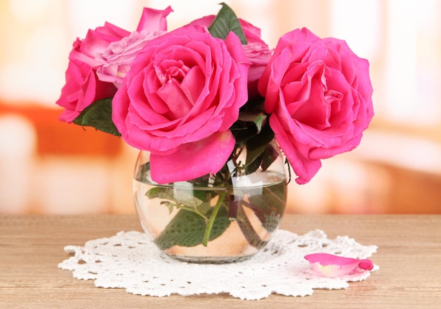 Belle rose rosa in vaso sul tavolo di legno sullo sfondo della stanza
