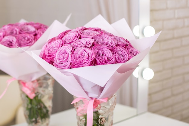 Belle rose rosa in vaso sul tavolo nel salone di bellezza, riflesso a specchio