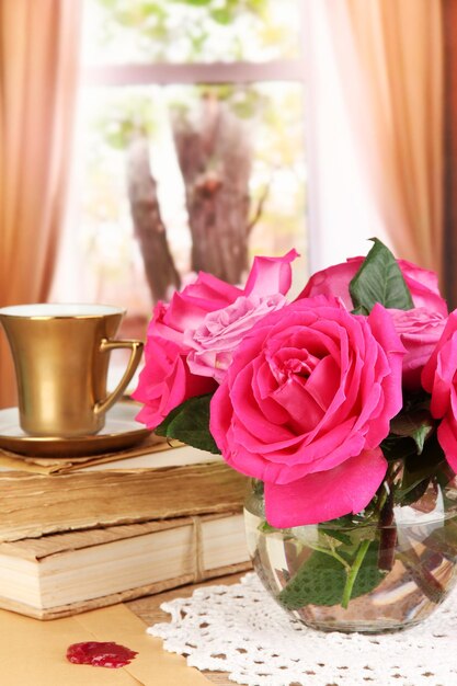 Belle rose rosa in vaso sulla tavola di legno sullo sfondo della finestra