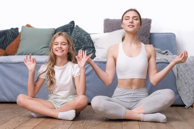 Belle sorelle che fanno yoga a casa esercizio felice della famiglia di sport