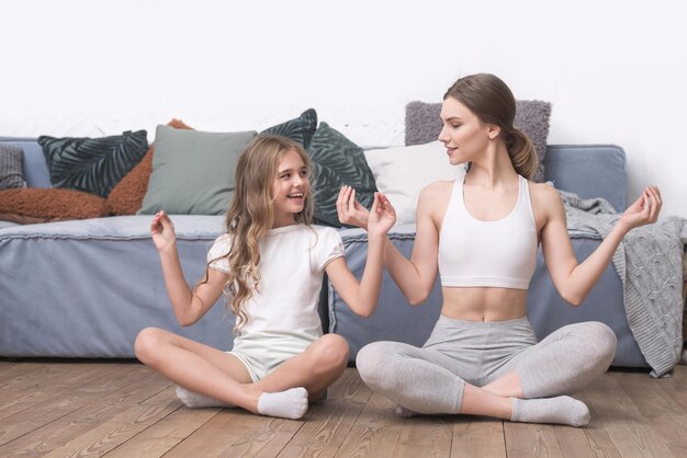 Belle sorelle che fanno yoga a casa esercizio felice della famiglia di sport