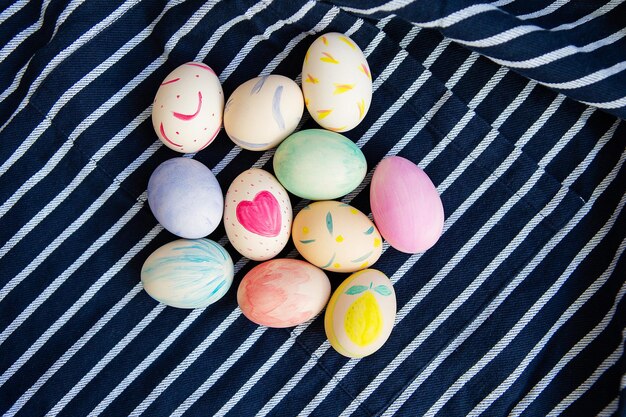 Belle uova di Pasqua dipinte con acquerelli giacciono su un tessuto blu a strisce
