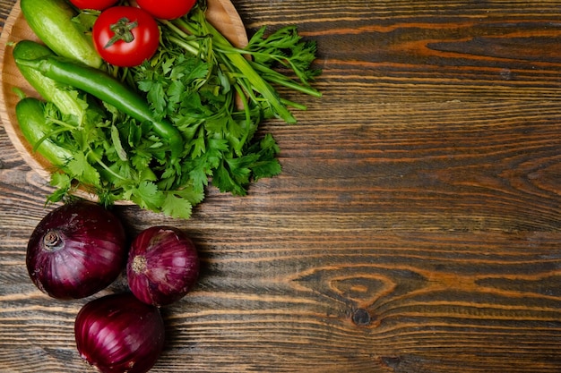 Belle verdure fresche del raccolto su tavola di legno con cappello di paglia Agricoltura agricola concetto di primavera o estate