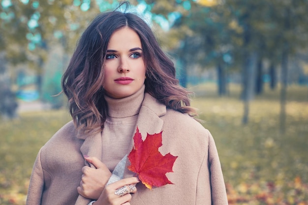 Bellezza autunnale. Donna carina con foglie autunnali nel parco autunnale all'aperto in giornata di sole