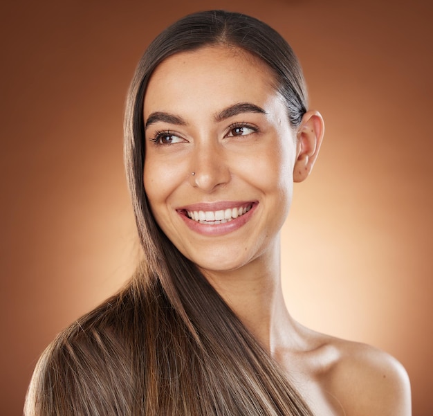 Bellezza dei capelli e cura della pelle con una donna modello in studio su sfondo marrone per un trattamento naturale o alla cheratina Cura dei capelli e salone del viso con una giovane donna attraente in posa per promuovere un prodotto