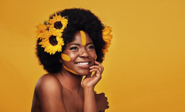 Bellezza del girasole e donna nera felice in studio per il benessere del trucco e il trattamento su sfondo giallo Cura della pelle del fiore e sorriso del modello femminile africano rilassarsi e posare con cosmetici naturali per la pelle