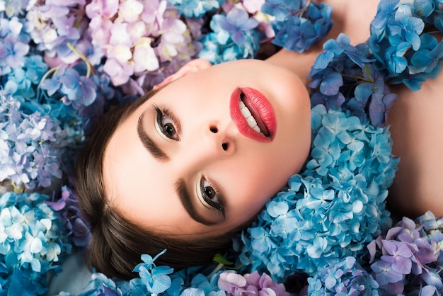 Bellezza della donna Ragazza sdraiata sui fiori Unità con la natura Blossom Cosmetici per il trucco e cura della pelle