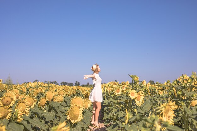 Bellezza donna illuminata dal sole sul campo di girasoli gialli Concetto di libertà e felicità Ragazza felice all'aperto