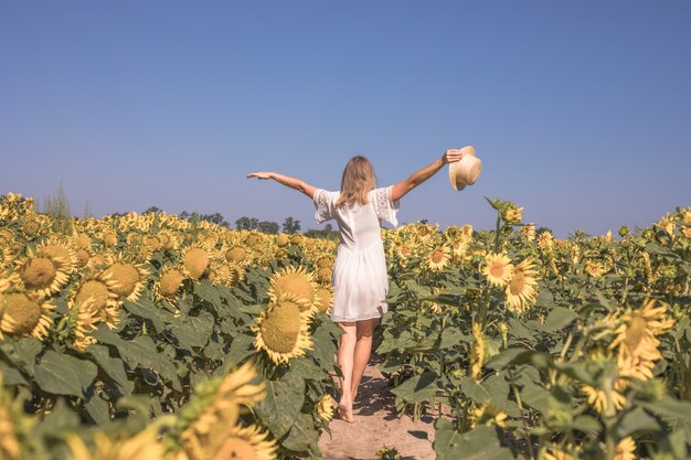 Bellezza donna illuminata dal sole sul campo di girasoli gialli Concetto di libertà e felicità Ragazza felice all'aperto